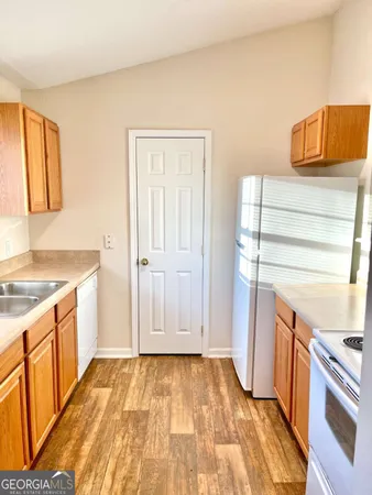 a view of a kitchen with fridge and wooden floor