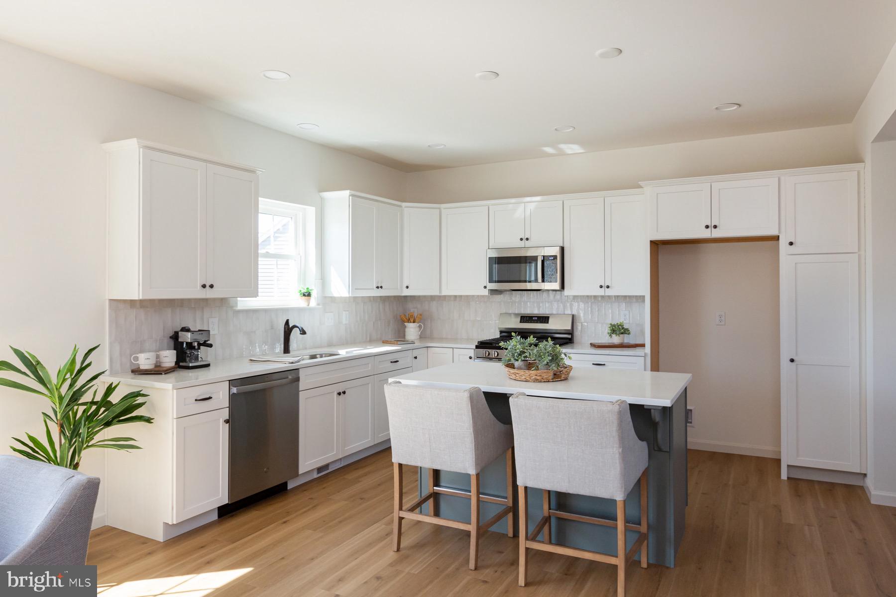 306 Wickmere Street, Unit 68 Oxford, PA 19363 - Photo 5 of 40 a white kitchen with a sink a stove a dining table and chairs