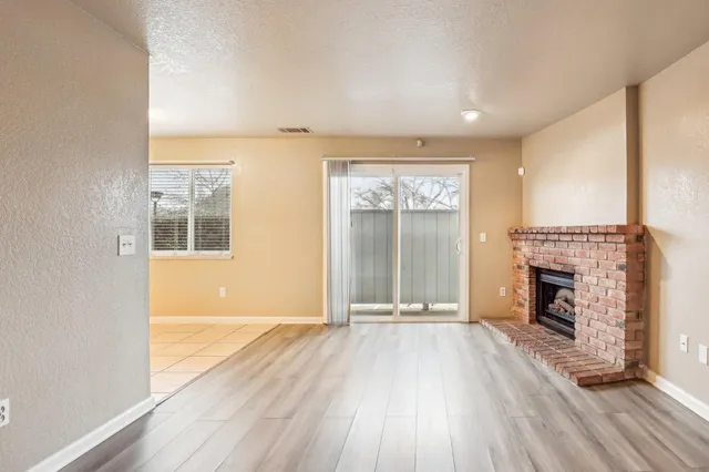 an empty room with wooden floor fireplace and windows