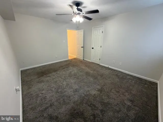 an empty room with closet and a ceiling fan