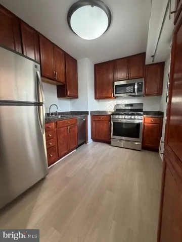 a kitchen with stainless steel appliances granite countertop a refrigerator stove a sink dishwasher and wooden cabinets