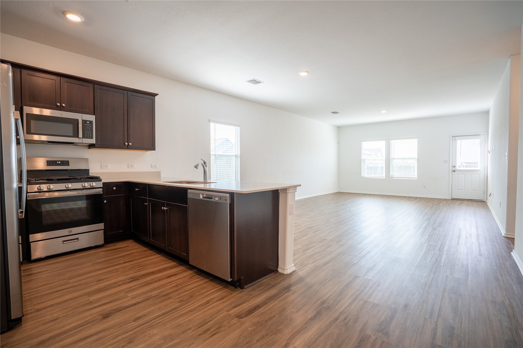 13400 Banquete Street Elgin, TX 78621 - Photo 29 of 29 Kitchen with stainless steel appliances, dark wood finish cabinets, a peninsula, open floor plan, and dark wood finished floors