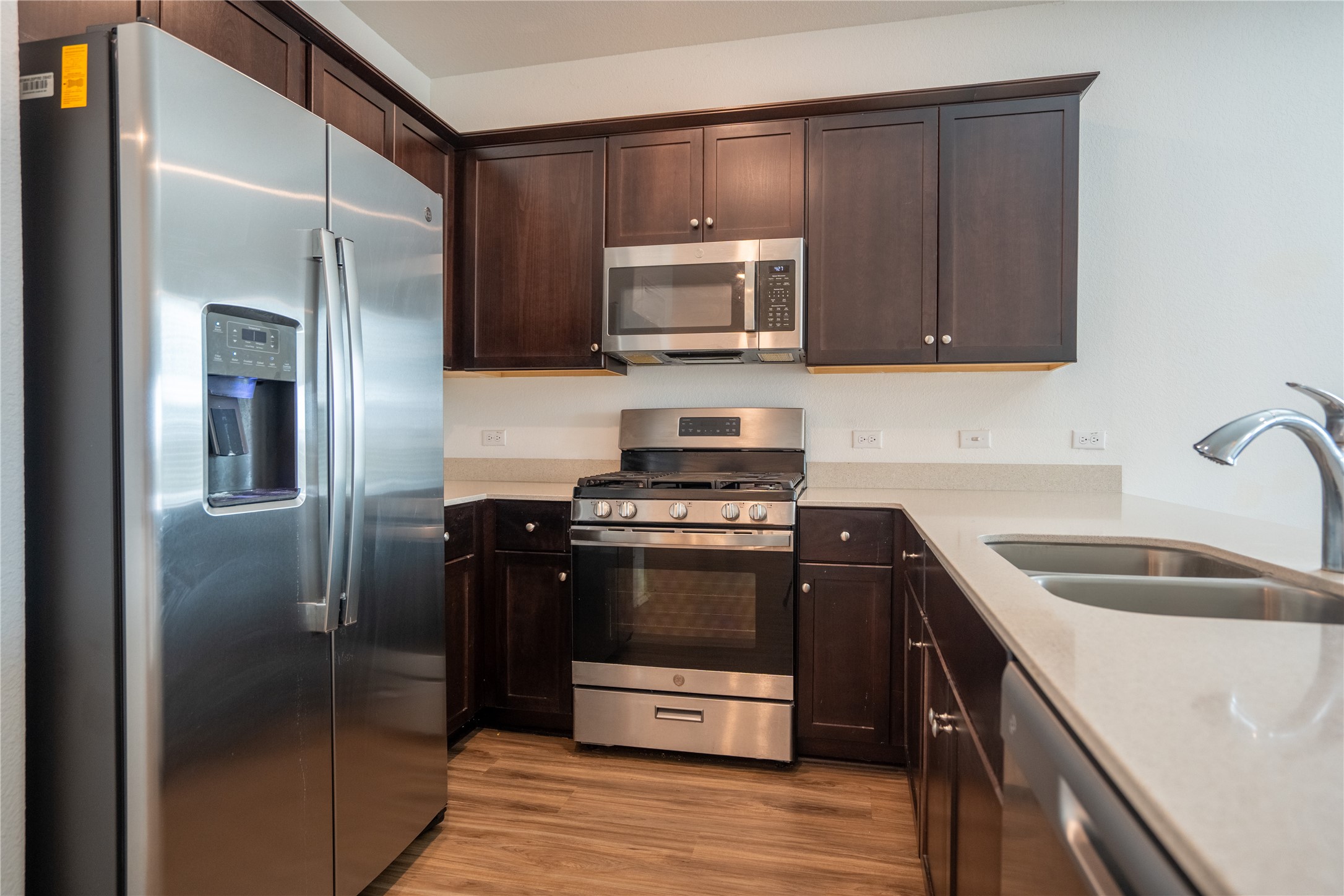 13400 Banquete Street Elgin, TX 78621 - Photo 7 of 29 Kitchen with stainless steel appliances, dark wood finish cabinetry, light stone counters, and light wood-type flooring