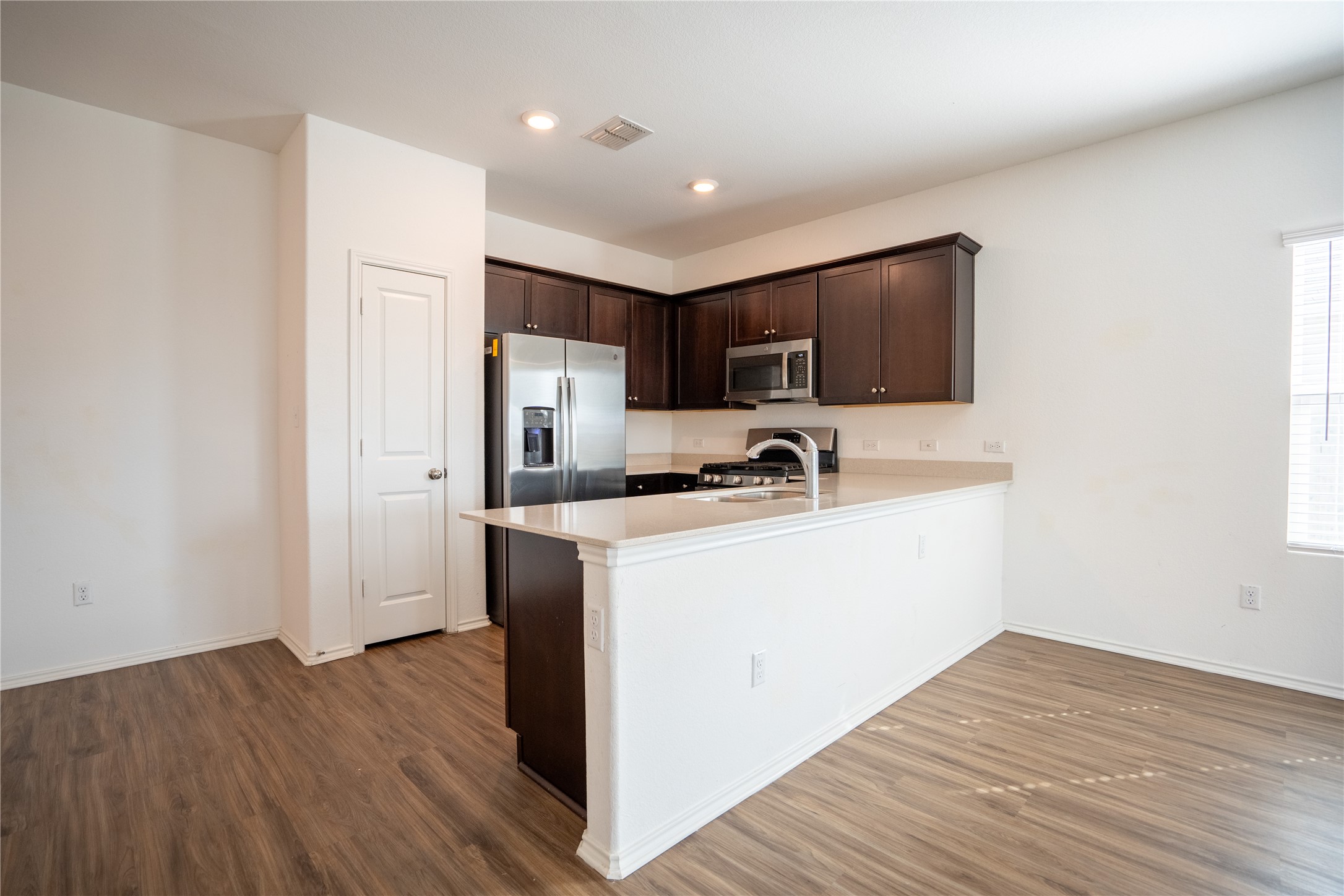 13400 Banquete Street Elgin, TX 78621 - Photo 8 of 29 Kitchen with dark wood finish cabinetry, stainless steel appliances, a peninsula, dark wood finished floors, and recessed lighting