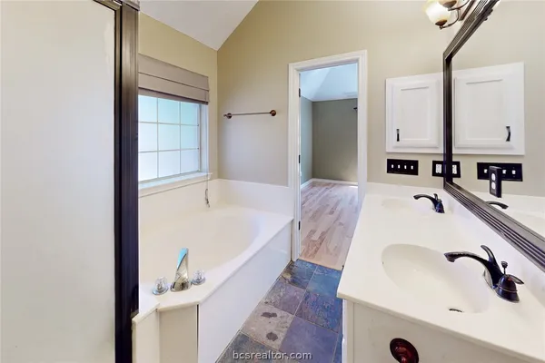 a bathroom with a tub sink and mirror