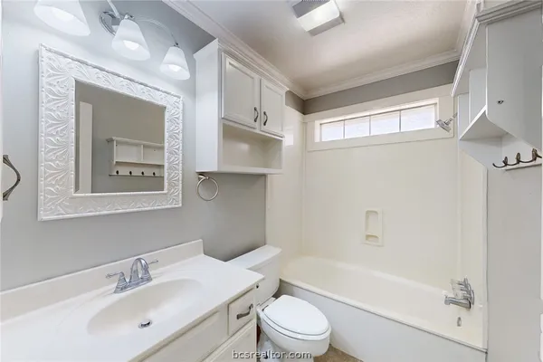 a bathroom with a bathtub shower sink vanity mirror and toilet