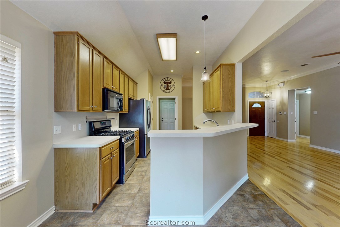 2817 Brandywine Circle Bryan, TX 77807 - Photo 10 of 28 a large kitchen with stainless steel appliances kitchen island a large counter top a stove a chimney a sink and a refrigerator