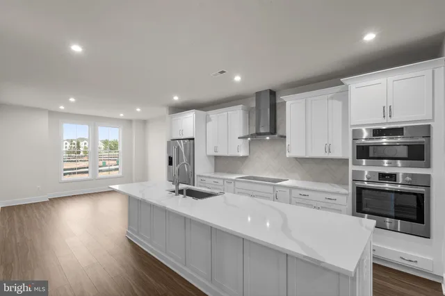 a kitchen with stainless steel appliances granite countertop a sink a stove a refrigerator and cabinets with wooden floor