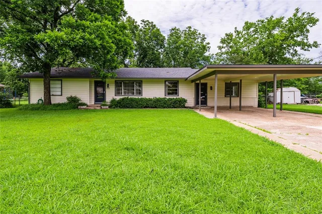 a front view of a house with a garden and trees