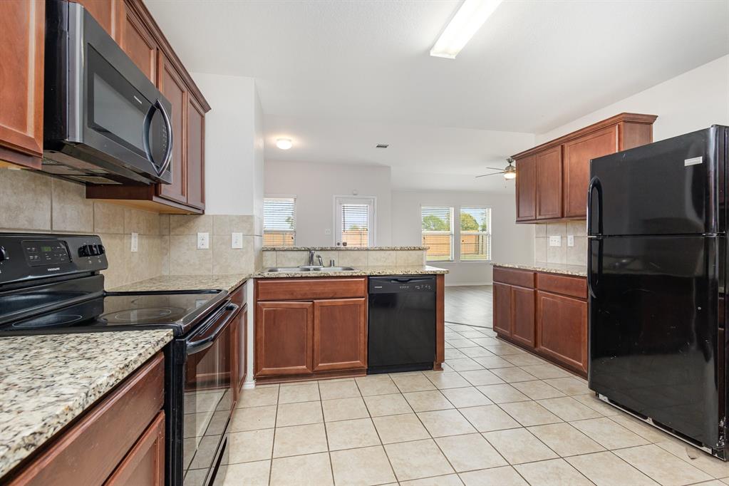 1025 Bend Court Forney, TX 75126 - Photo 5 of 12 a kitchen with stainless steel appliances granite countertop a stove refrigerator and a microwave