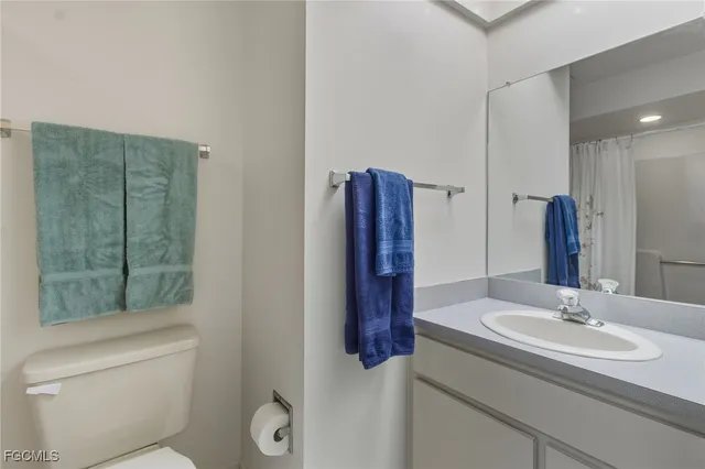 a bathroom with a granite countertop sink a toilet a mirror and shower