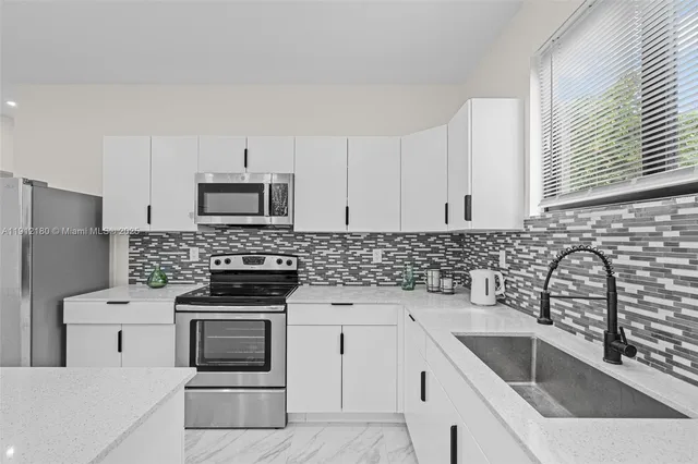 a kitchen with white cabinets sink and stainless steel appliances