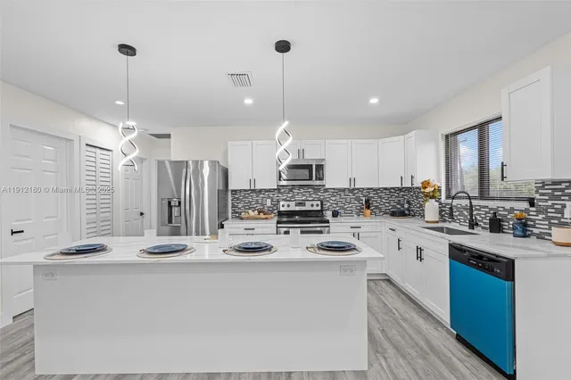 a kitchen with stainless steel appliances kitchen island a stove a sink a center island and a window