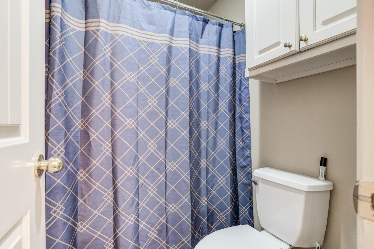 3114 109th Street Lubbock, TX 79423 - Photo 19 of 43 a white toilet sitting next to a shower curtain