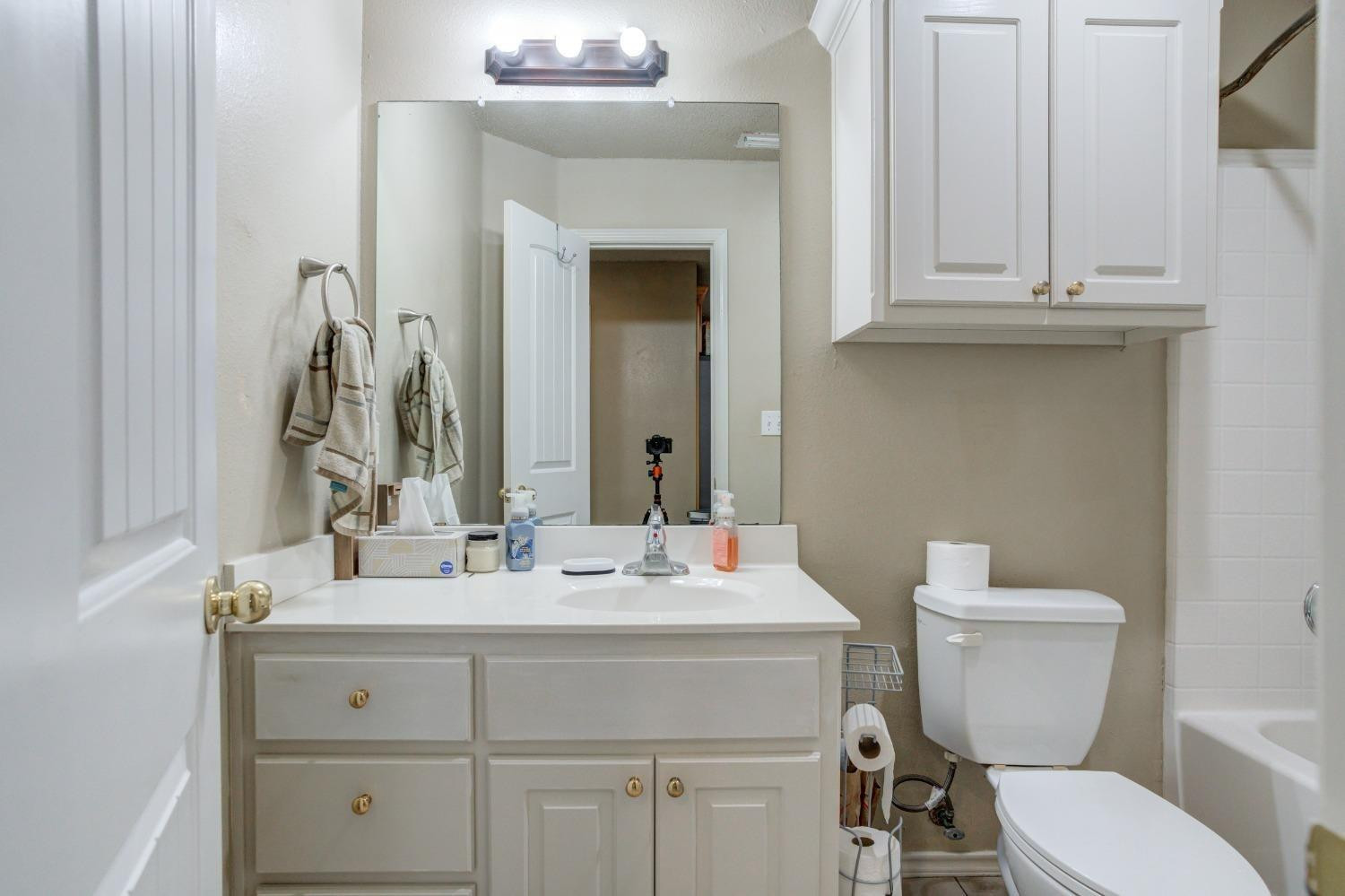 3114 109th Street Lubbock, TX 79423 - Photo 23 of 43 a bathroom with a toilet sink and mirror