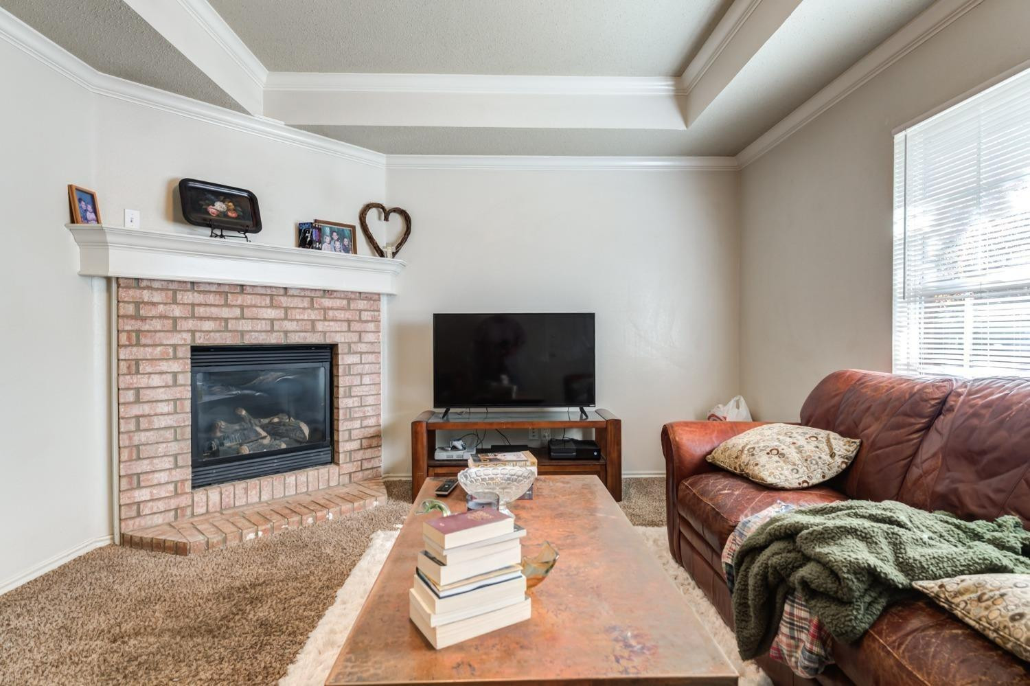 3114 109th Street Lubbock, TX 79423 - Photo 33 of 43 a living room with furniture a flat screen tv and a fireplace