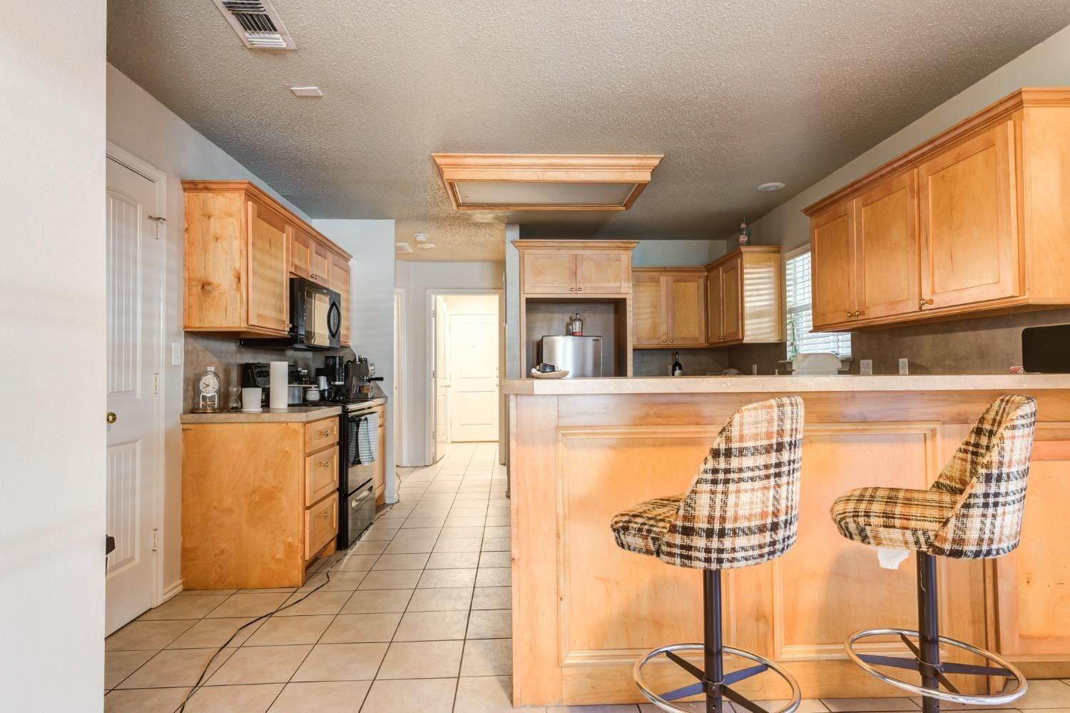 3114 109th Street Lubbock, TX 79423 - Photo 35 of 43 a kitchen with stainless steel appliances kitchen island granite countertop a refrigerator a stove a sink dishwasher and white cabinets with wooden floor
