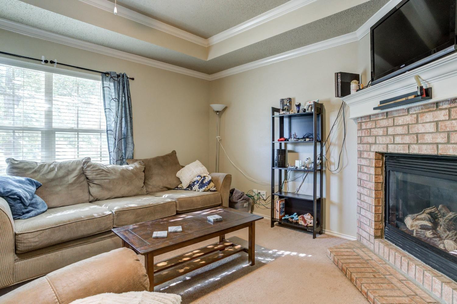3114 109th Street Lubbock, TX 79423 - Photo 6 of 43 a living room with furniture a flat screen tv and a fireplace