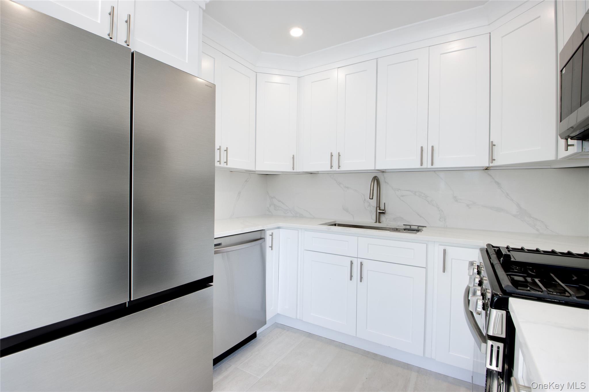 46 Linwood Road North Port Washington, NY 11050 - Photo 14 of 19 a kitchen with stainless steel appliances a refrigerator a sink and white cabinets