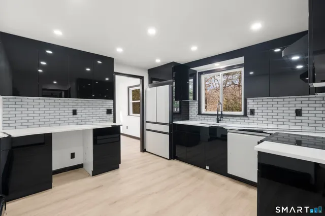 a kitchen with stainless steel appliances kitchen island granite countertop a sink and stove top oven with wooden floor