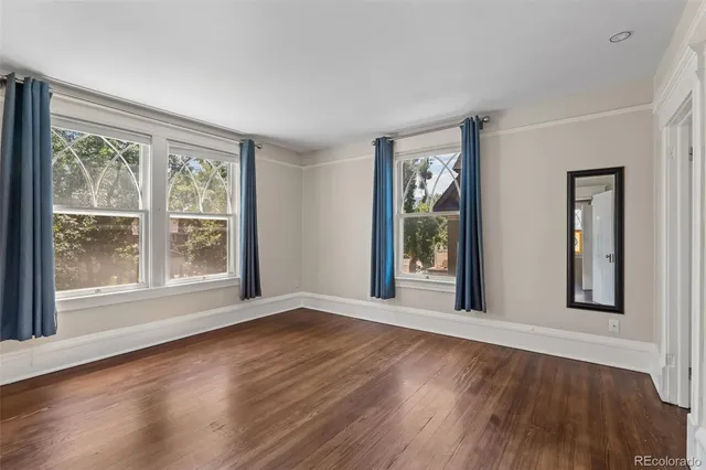 a view of an empty room with wooden floor and windows