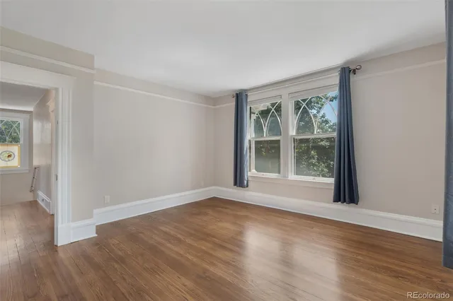 a view of an empty room with wooden floor and a window