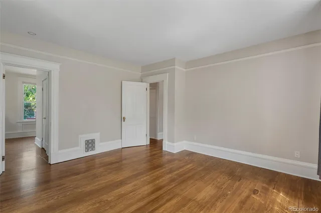 a view of an empty room with wooden floor and closet