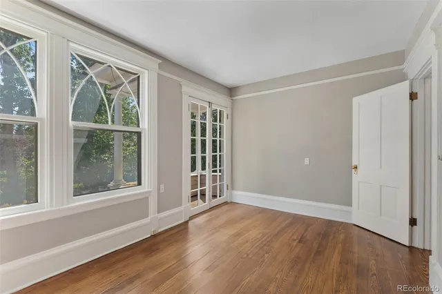 a view of an empty room with wooden floor and windows