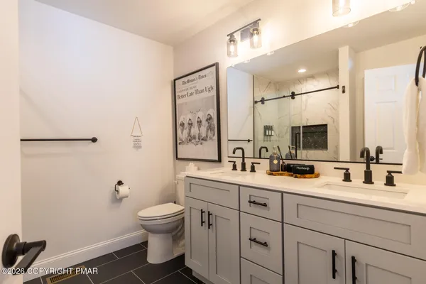 a bathroom with a toilet sink double vanity and mirror