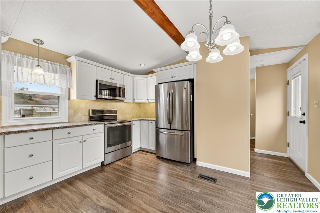 12 Revolutionary Road Mount Bethel, PA 18343 - Photo 13 of 53 a large kitchen with stainless steel appliances granite countertop a refrigerator a microwave oven a sink dishwasher and white cabinets with wooden floor