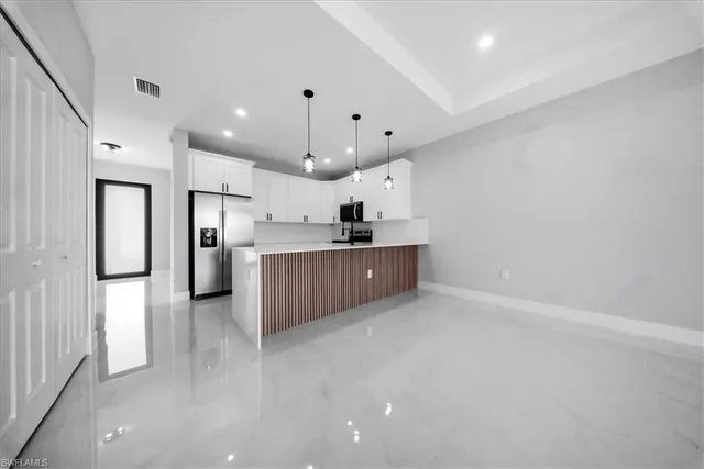 a kitchen with stainless steel appliances kitchen island a refrigerator sink and cabinets