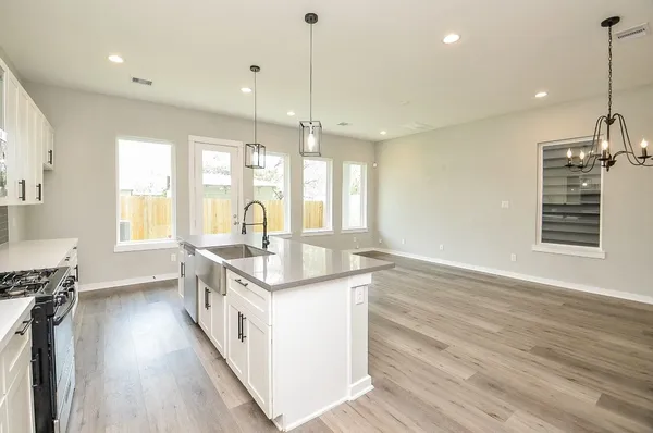 a kitchen with stainless steel appliances granite countertop a sink a stove and a wooden floors