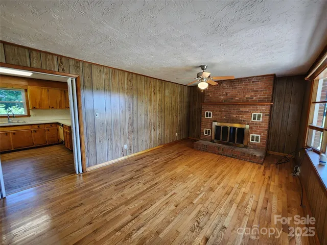 an empty room with wooden floor fireplace and windows