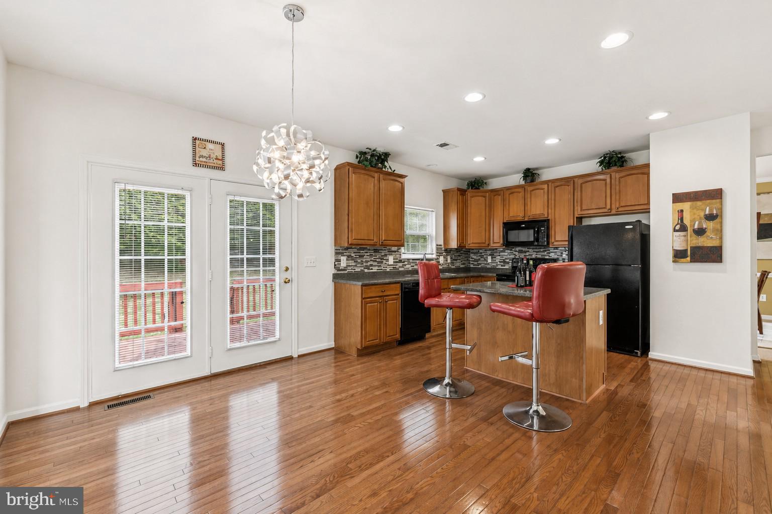 10103 Rolling Green Way Fort Washington, MD 20744 - Photo 7 of 39 a kitchen with stainless steel appliances kitchen island granite countertop a refrigerator a stove top oven a sink dishwasher and a dining table with wooden floor