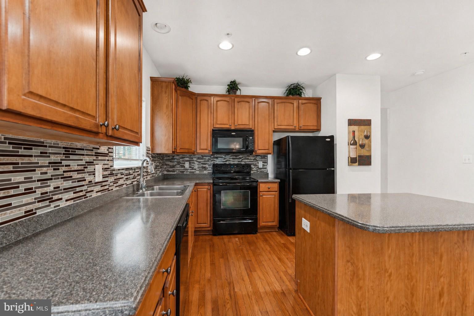 10103 Rolling Green Way Fort Washington, MD 20744 - Photo 9 of 39 a kitchen with stainless steel appliances granite countertop a refrigerator a stove and a sink with wooden floor