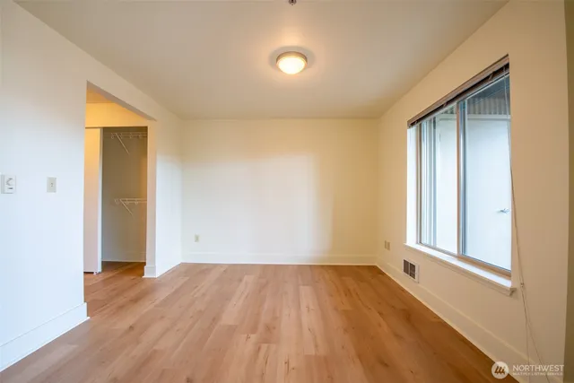 an empty room with wooden floor and windows