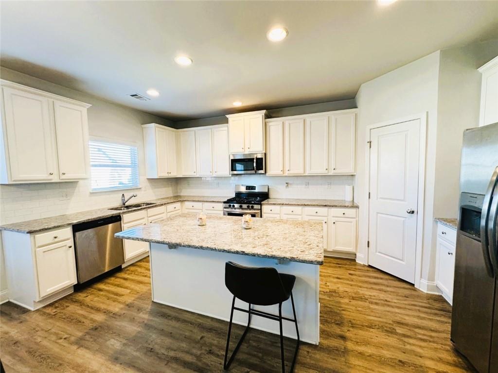 142 Wentworth Lane Villa Rica, GA 30180 - Photo 12 of 44 a kitchen with stainless steel appliances granite countertop a stove a sink dishwasher and a refrigerator with wooden floor