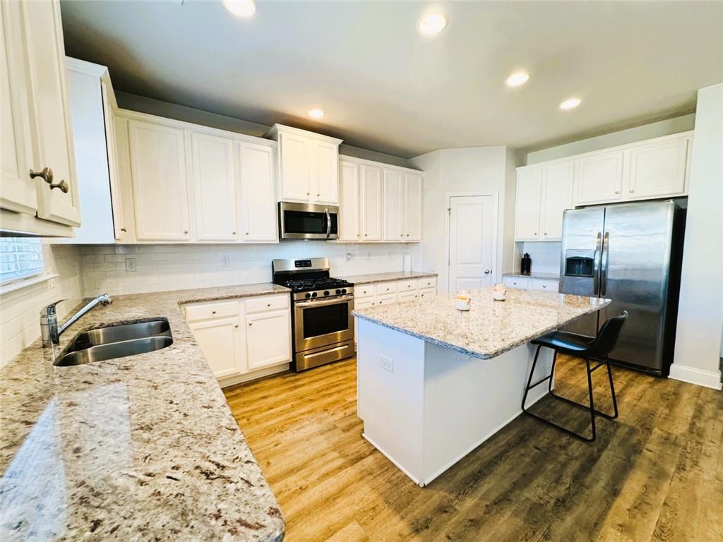 142 Wentworth Lane Villa Rica, GA 30180 - Photo 13 of 44 a kitchen with stainless steel appliances granite countertop a sink a stove a refrigerator a microwave oven with white cabinets and wooden floor