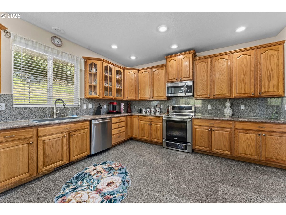 5122 Southeast Jenne Road Portland, OR 97236 - Photo 24 of 36 a kitchen with stainless steel appliances kitchen island granite countertop a stove sink and cabinets