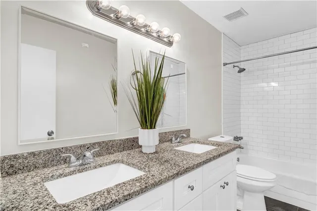 a bathroom with a granite countertop sink a toilet and a mirror