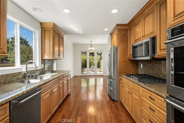 a kitchen with stainless steel appliances granite countertop a refrigerator a sink and a stove