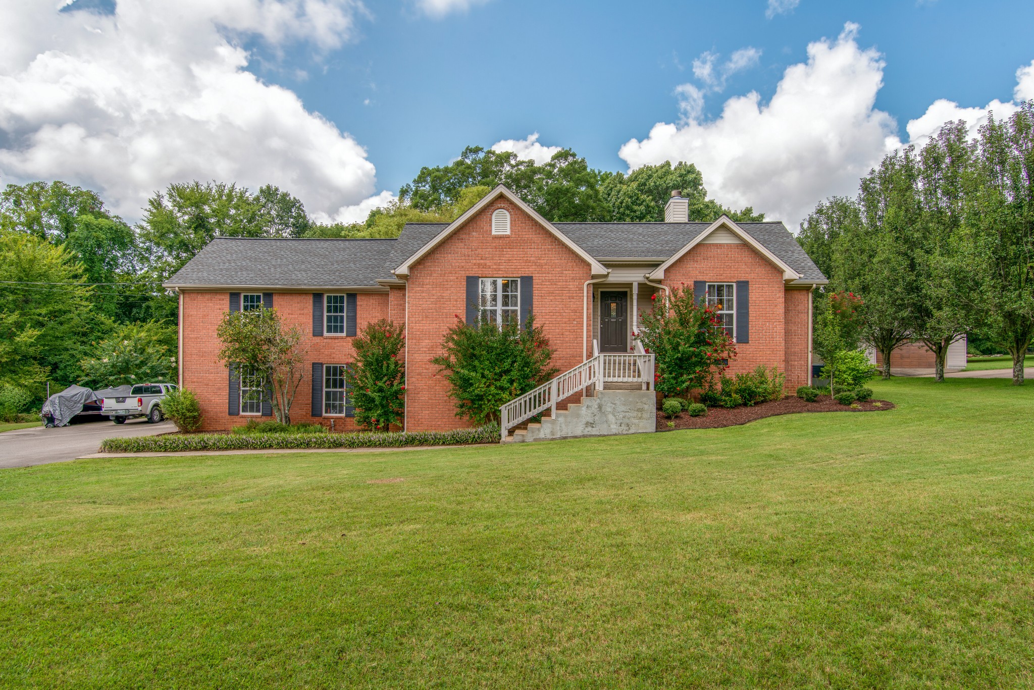 a front view of a house with a garden and trees