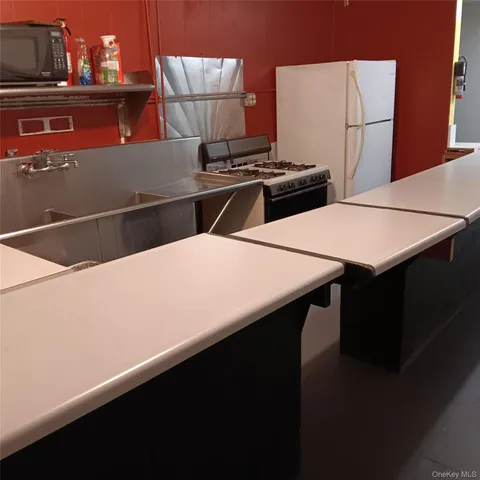 a kitchen with a stove two chairs and a refrigerator