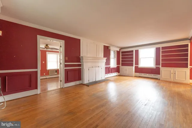 an empty room with wooden floor and windows