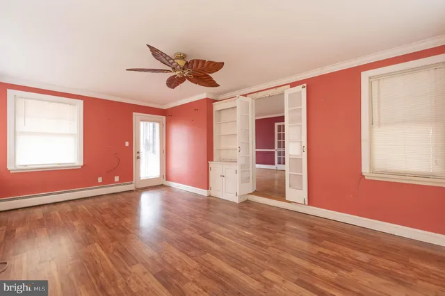 a view of an empty room with wooden floor and a window