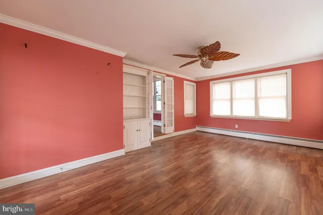 a view of an empty room with a window and wooden floor