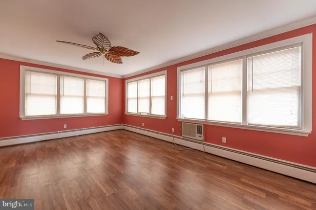 a view of an empty room with a window and wooden floor