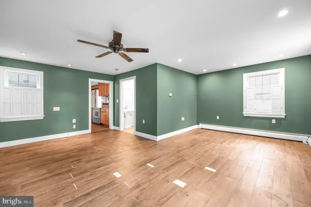 a view of an empty room with window and wooden floor