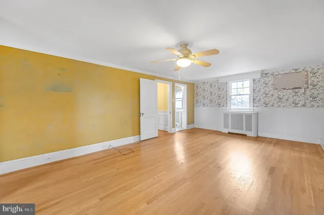 a view of an empty room with a window and wooden floor