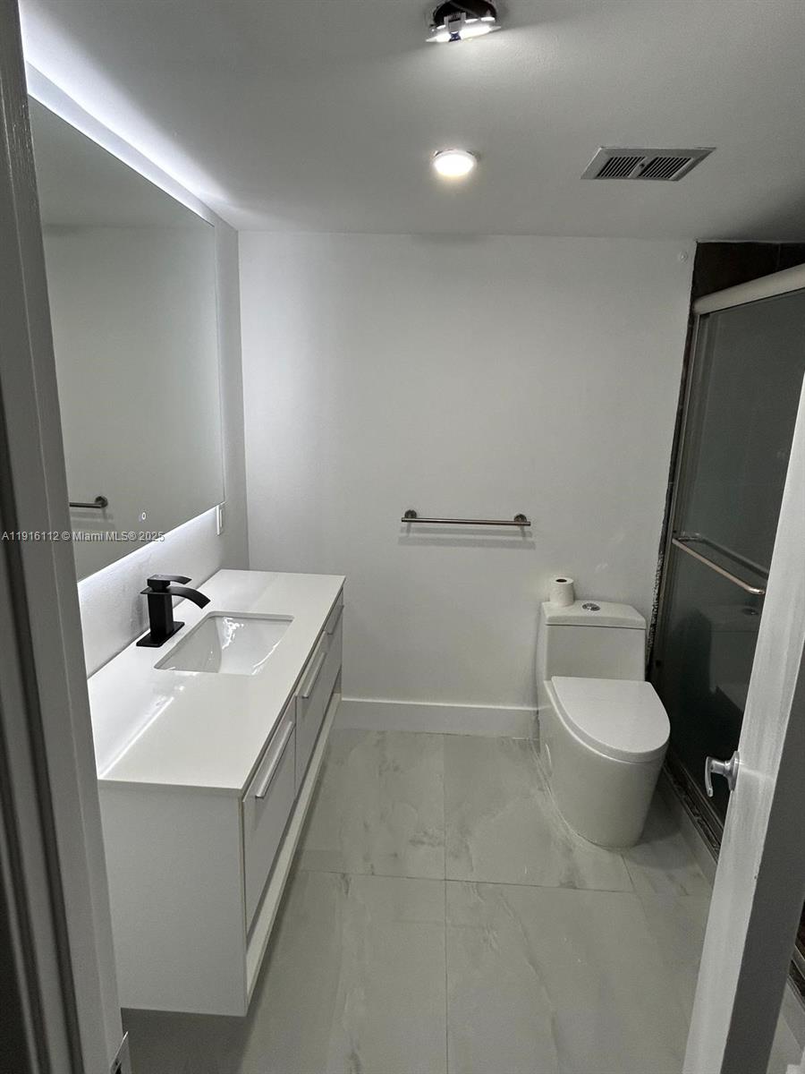 1750 Northeast 191st Street, Unit 4264 Miami, FL 33179 - Photo 16 of 21 a bathroom with a toilet a sink and mirror